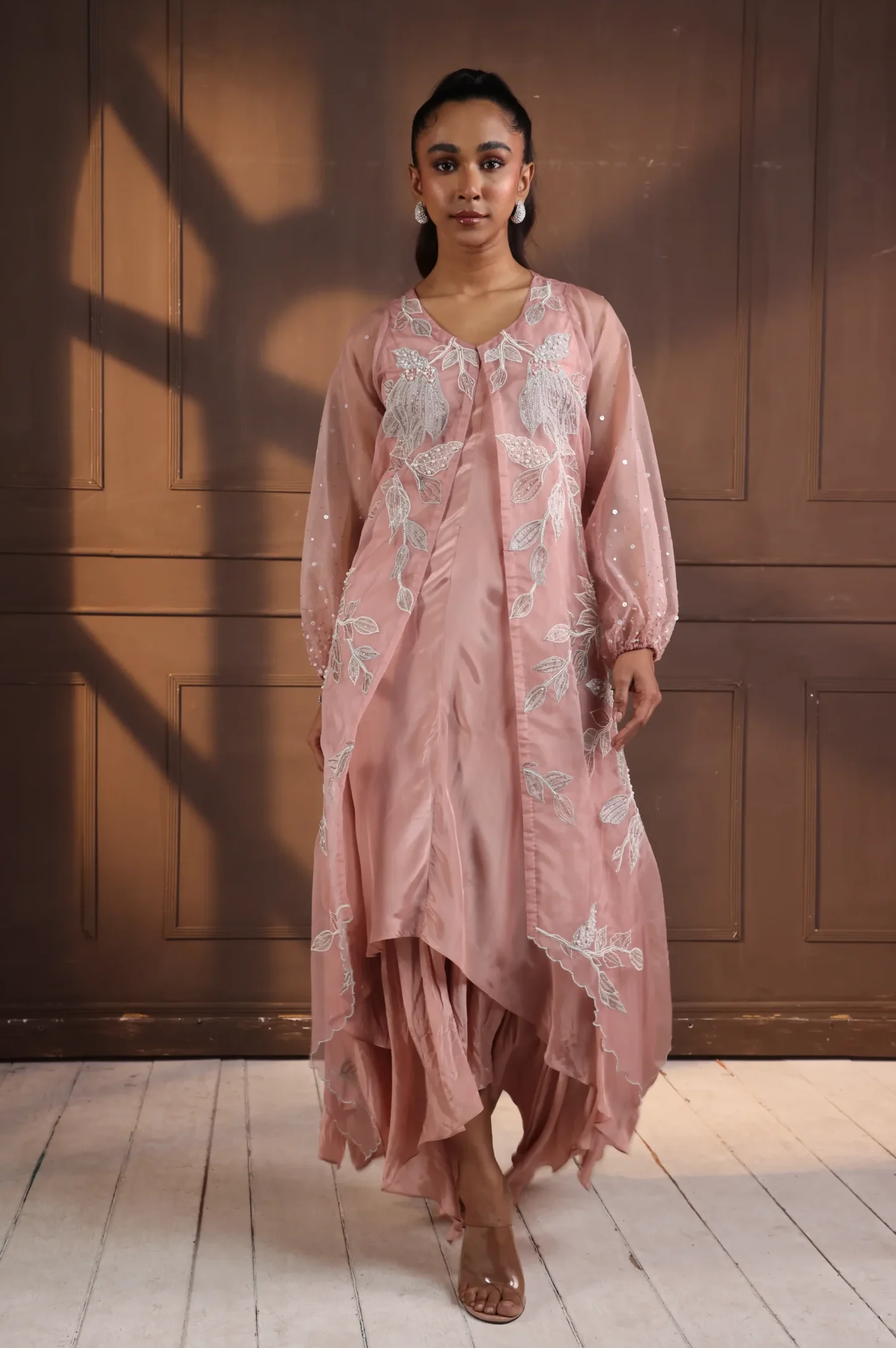 Model wearing dusty rose golden muslin handkerchief hem dress with silver floral embroidery and sheer long sleeves