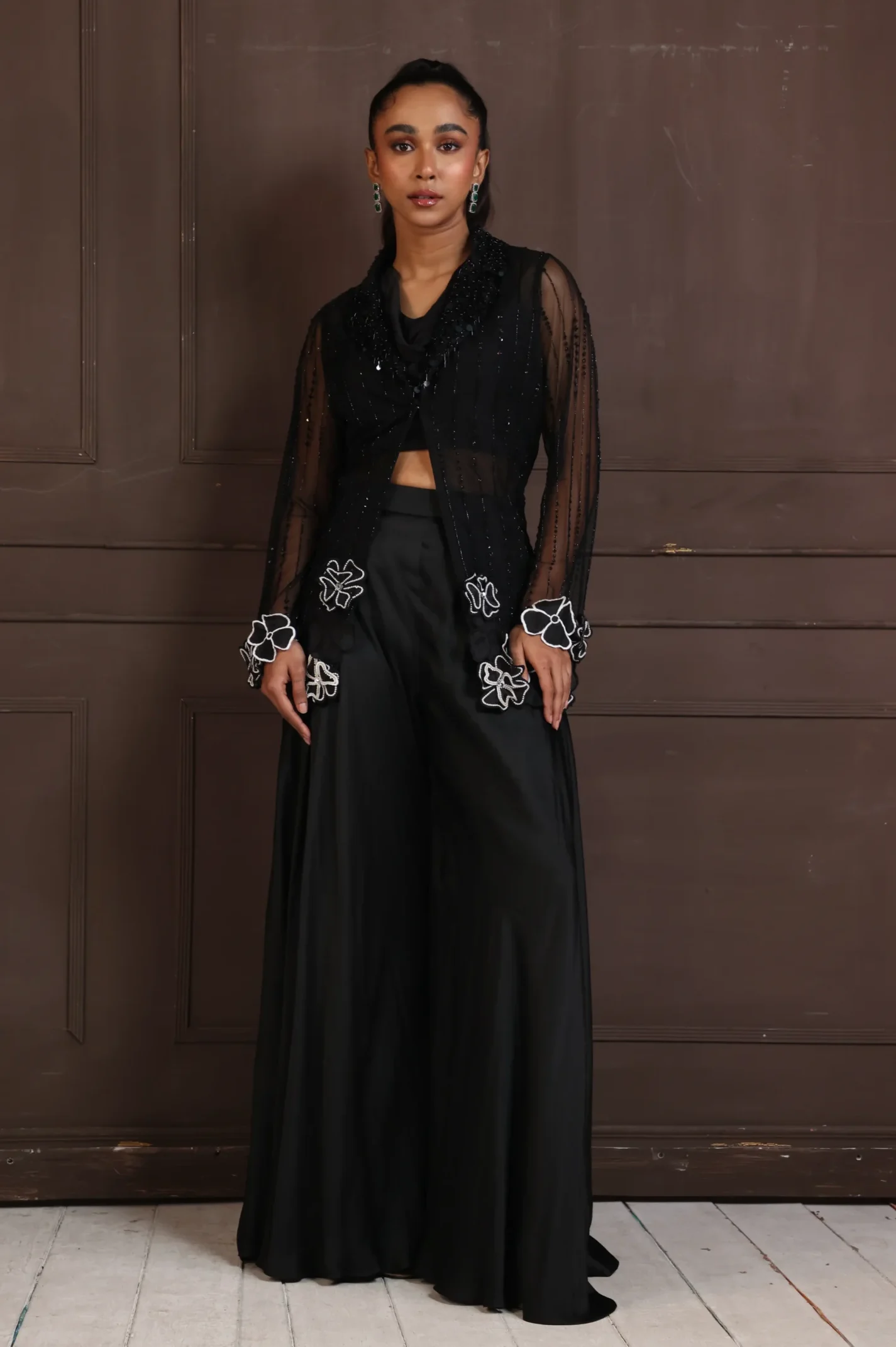 Model wearing black golden muslin bold evening co ord set with sheer panel bodice and wide leg palazzo trousers